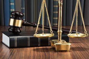 Justice scale, gavel, and law book resting on a table.